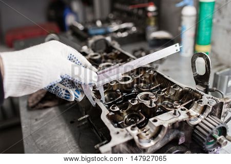 Mechanic, using a calipher, to check the thickness. Full engine major repairs. Hardware bathroom