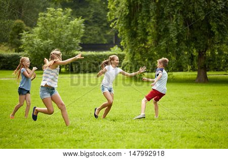 friendship, childhood, leisure and people concept - group of happy kids or friends playing catch-up game and running in summer park