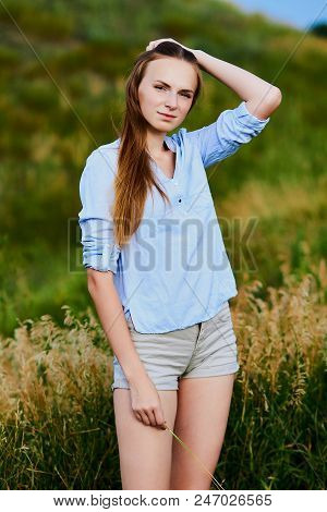 Happy Smiling Young Girl In Blue Shirt And Shorts In The Field
