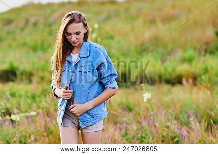 Happy Smiling Young Girl Wearing Blue Jeans Jacket And Shorts Is Standing In The Field