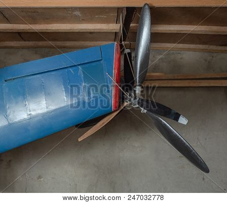 Blue Airplane Wing Of Model Aircraft With Propeller Hanging On A Wooden Shelf Of Vehicle Spung. Airs