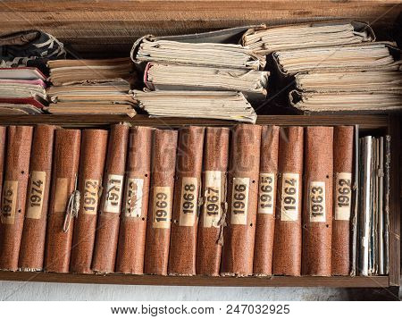 Old Books On Wooden Bookshelf. Brown Books Standing In A Row On Wooden Shelf. Vintage Shabby Books O