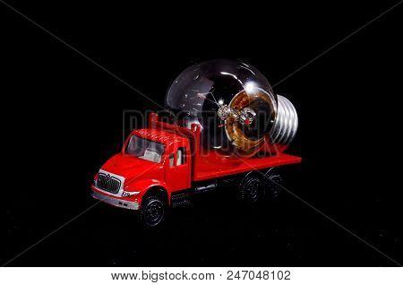 Electric Power Concept Red Truck And Light Bulb On A Black Background