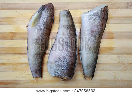 Three Pieces Of Fish Notothenia On A Cutting Board Close-up