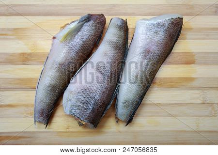 Three Pieces Of Fish Notothenia On A Cutting Board Close-up