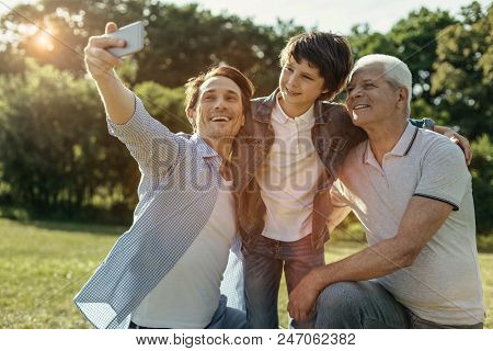 Say Cheese. Smiling Relaxed Full Of Life Dad Son And Grandfather Taking A Selfie While Hugging And L