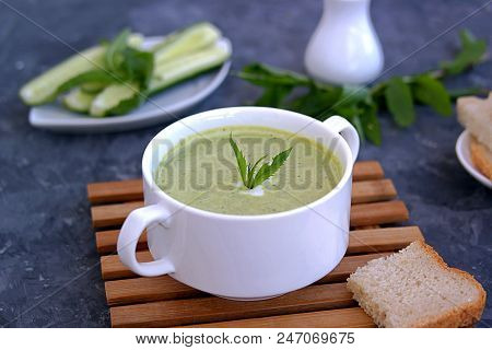 Summer Cold Yoghurt Soup With Fresh Cucumber, Green Peas And Mint On A Gray Concrete Background