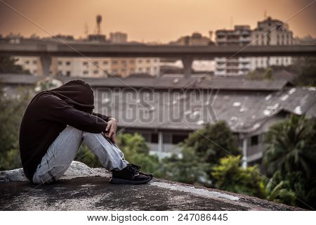 Young Asian Man Sitting On Rooftop Of Abandoned Building With Depression Stress Out During Sunset Ti