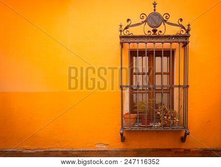 Antique Medieval Window With Rusty Iron Bars And Russet Orange Orange Wall In Old Santa Cruz Quarter