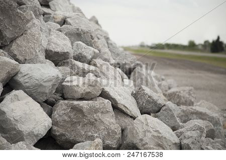 Large Pile Of Grey Bolder Rocks And The Road