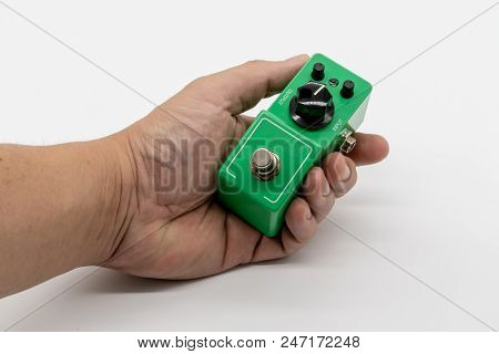 Hand Holding Green Vintage Guitar Pedal Isolated On White Background