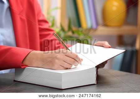 Female Author Signing Autograph In Book At Table Indoors, Closeup