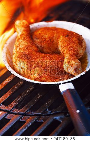 chicken legs spiced by special spice blend on bbq grill with flame