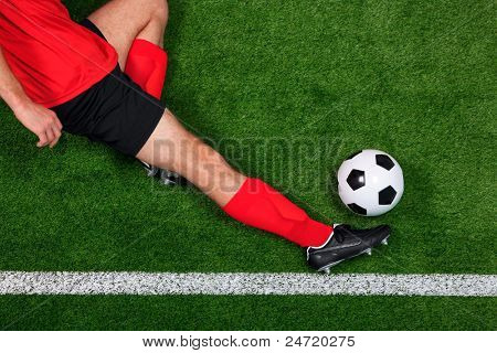 Overhead photo of a football or soccer player sliding in to save the ball going over the sideline