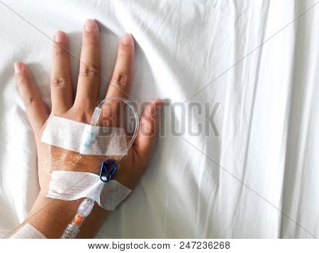 Patient Hand With The Tube Of Normal Saline Infusion On White Cloth Background