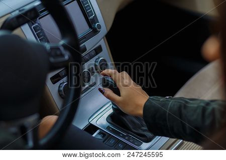 Girls Hands Are Aestetically Situated On The Transmission To Shift Gear Of A Grey Car.