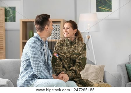 Woman In Military Uniform With Her Husband On Sofa At Home