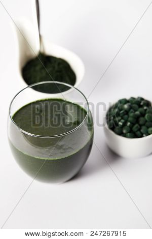 Close Up View Of Fresh Spirulina Drink In Glass, Spirulina Powder And Spirulina Pills In Bowls On Gr