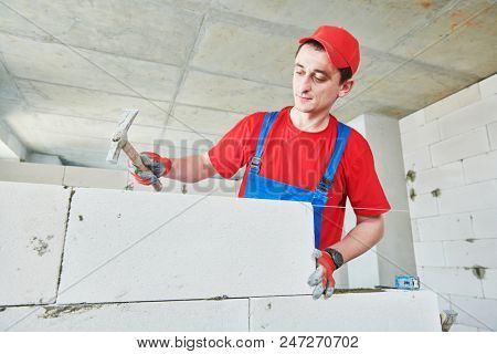 walling. bricklayer installing autoclaved aerated concrete blocks.