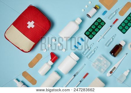Top View Of First Aid Kit Bag With Composed Medicines On Blue Surface