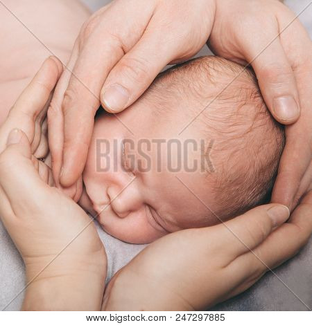 Portrait Of Newborn Baby Lying On The Hands Of Parents. The Concept Of Newborn Health