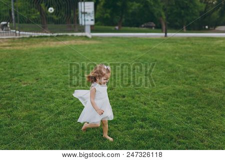 Pretty Little Cute Child Baby Girl In Light Dress Running, Catching Up And Have Fun On Green Grass L