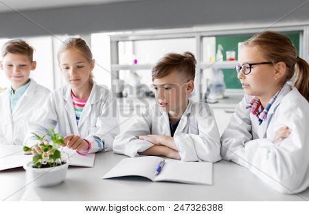 education, science and school concept - kids or students with plant at biology class