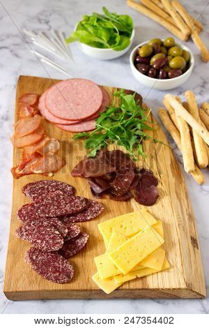 Appetizer Table For Wine Or Beer With Sausages, Dried Meat And Cheese, Served With Grissini, Herbs A