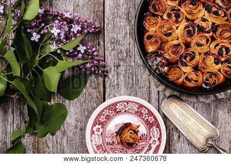 Homemade Mini Cherry Rolls In A Baking Form And One Roll On A Plate With Bouquet Of Lilac On Vintage