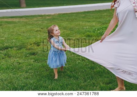 Little Cute Child Baby Girl Running Catching Up Have Fun With Joyful Woman In Light Dress On Green G