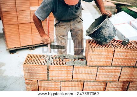 Industrial Mason Using Trowel, Pan Knife And Mortar For Brickwork, Building Outside Walls