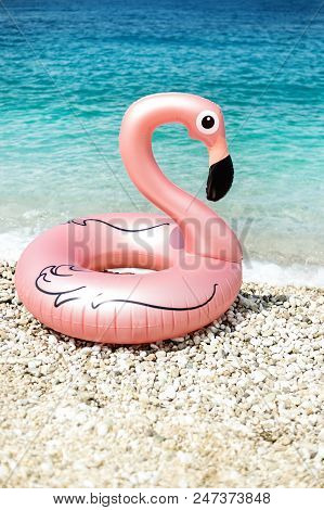 Giant Inflated Flamingo Float On A Beach With Turquois Water Of Ionian Sea Albania In Background