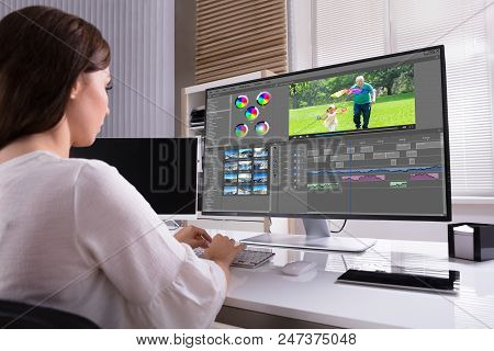 Young Female Editor Editing Video On Computer In Office
