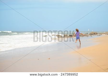 Happy Girl In Purple Swimsuit Running On The Beach In The Waves, Family On Vacation, View From Behin