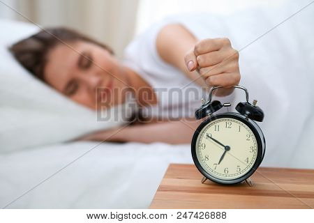 Sleepy Young Woman Stretching Hand To Ringing Alarm Willing Turn It Off. Early Wake Up, Not Getting 