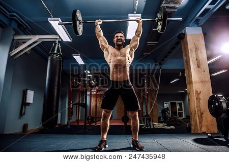Muscular Fitness Man Doing Deadlift A Barbell Over His Head In Modern Fitness Center. Functional Tra