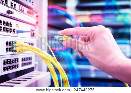 hand with network cables connected to servers in datacenter