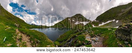 Panorama Of Capra Lake, Romania. Gorgeous Landscape Of Fagarasan Mountains On A Cloudy Summer Day