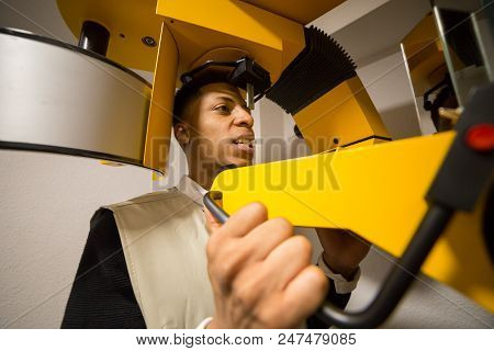Crop View Of Black Male Making X-ray Examination Of Teeth On Colorful Machine.