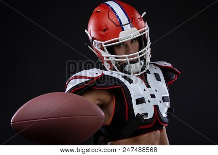 Sportive Serious Woman In Helmet Of Rugby Player Holding Ball In Stuio On Black Background. Gender E