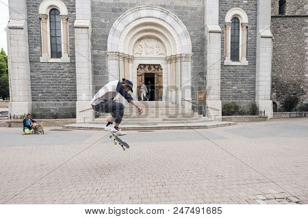 Barcelonnette, France, 8 June 2018: Boy Stunts On Skate Board In Front Of Catholic Church Of Barcelo