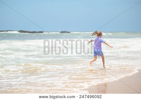 Happy Girl In Purple Swimsuit Running On The Beach In The Waves, Family On Vacation, View From Behin