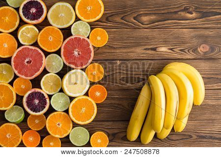 Mixed Cut Ripe Tropical Citrus Fruit With A Bunch Of Yellow Bananas On A Textured Wood Background Wi