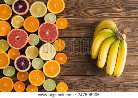 Colorful Still Life Display Of Assorted Fresh Halved Citrus Fruit And A Bunch Of Ripe Yellow Bananas