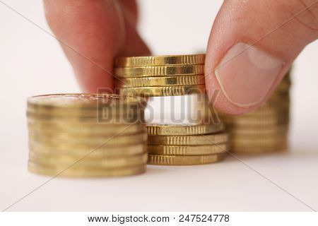 Fingers Taking Or Placing Golden Coins From Stac Or Piles Of Money. Close Up Og Hand And Money Piles
