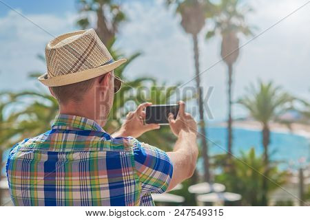 Man In Sunhat Making Photo Of Amazing Sea View With His Smartphone. Santa Susanna. Cataluna. Spain.