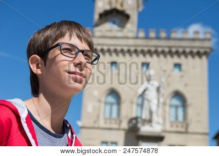 Young boy spectacled looking up outdoor over San Marino city-state. Vision, eyesight, sight, diopters, spectacles, glasses, health.