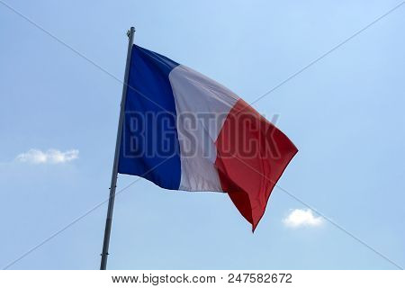 Flag Of France Against A Blue Sky With Clouds.