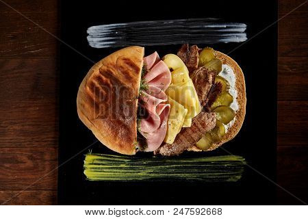 Tasty Jewish Pita Stuffed With Grilled Meat, Ham, Cheese, Piccoli And Sauce On Black Square Plate Ov