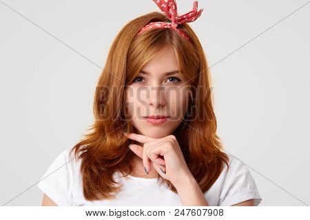 Self Confident Young Beautiful Female Holds Chin And Looks Seriously At Camera, Wears Stylish Headba